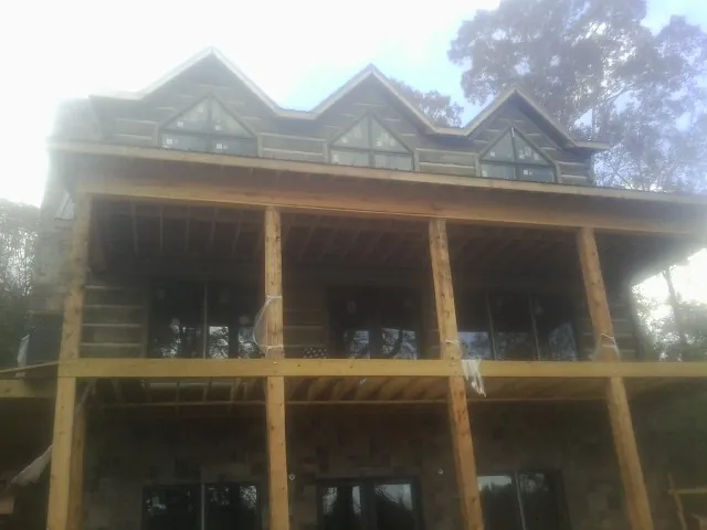 Dormers and porch framing on a large log home under construction — Roof Coating work by our crew in Verona